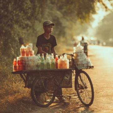 暑期的8月早上的三界鎮街頭吃包子，一輛賣西瓜的三輪車停在馬路邊，老伯正在稱西瓜。